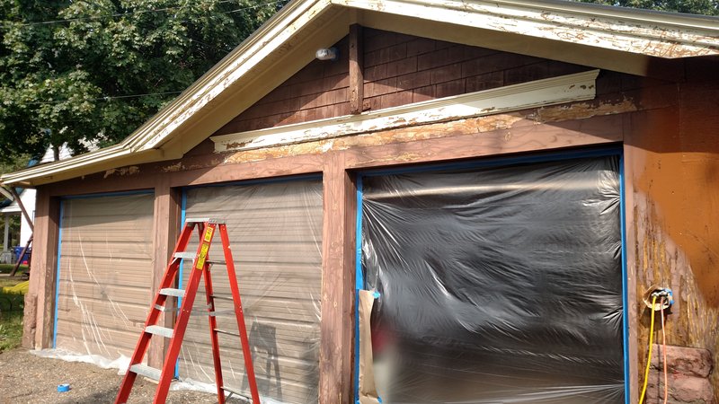 Garage mid-paint with ladders and drop cloths