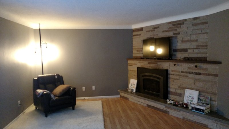 Finished living room with gray walls and stone fireplace