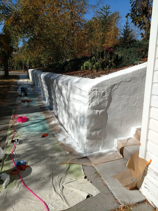 Curved wall being painted with drop cloths